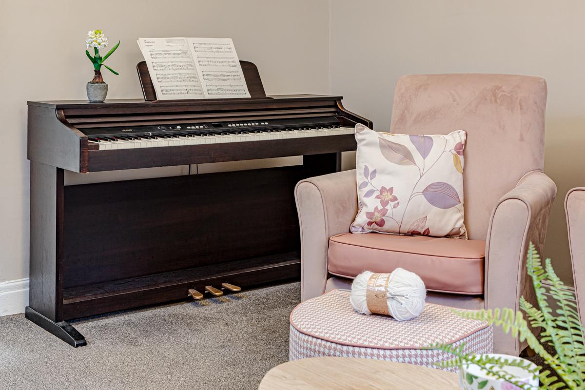 pink armchair next to an upright piano