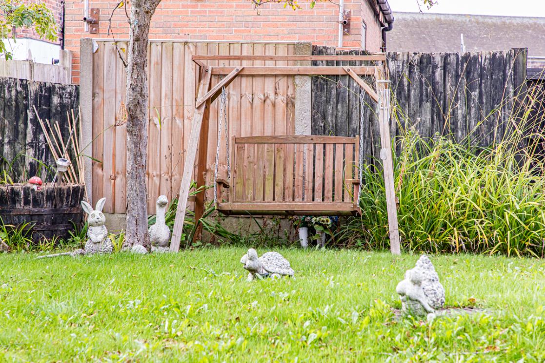 flat grass lawn with stone decorations and swinging bench