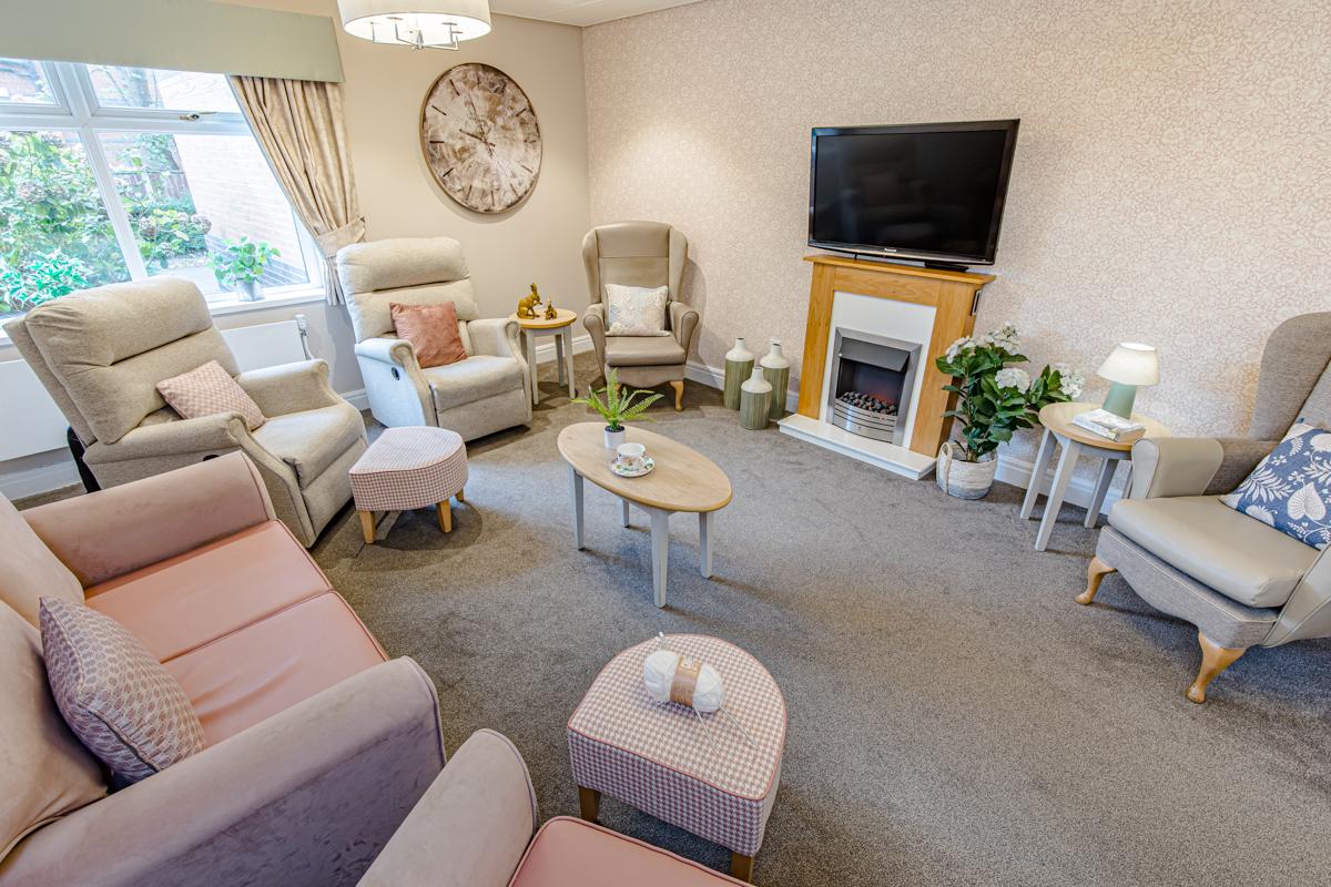 spacious care home lounge with fireplace and television