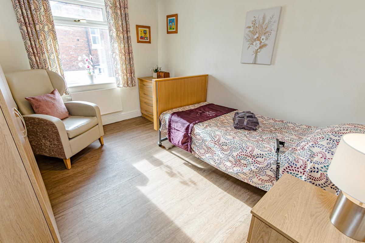 care home bedroom with patterned sheets and sunny window